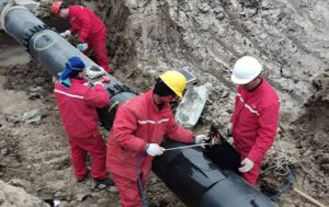 Workers in red work clothes install large-diameter pipeline (for natural gas/oil pipeline relocation project) at construction site, Suqian, Jiangsu