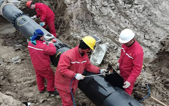 Workers in red work clothes install large-diameter pipeline (for natural gas/oil pipeline relocation project) at construction site, Suqian, Jiangsu