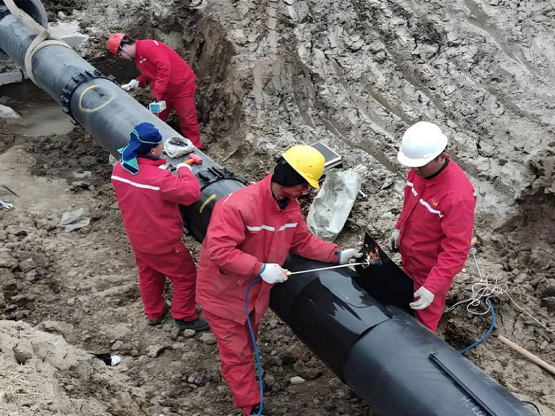 Workers in red uniforms installing large-diameter pipeline at Suqian natural gas pipeline relocation site