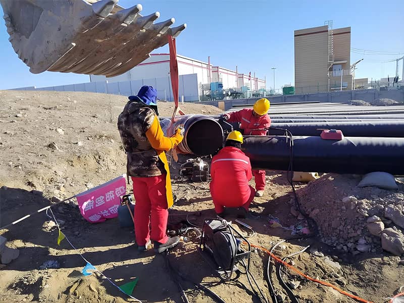 Ulanqab DN500 natural gas pipeline project welding construction with workers and excavator on site.