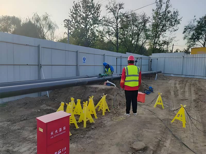 Construction site of Wenchao Canal pipeline relocation project, showing workers and safety equipment.