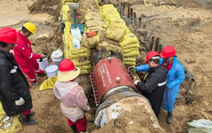 Technicians precisely installing A-type epoxy sleeve on damaged section of natural gas transmission pipeline during emergency repair