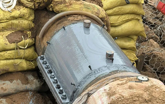 Certified pipeline technician performing bolt tightening and quality control check on installed epoxy sleeve reinforcement