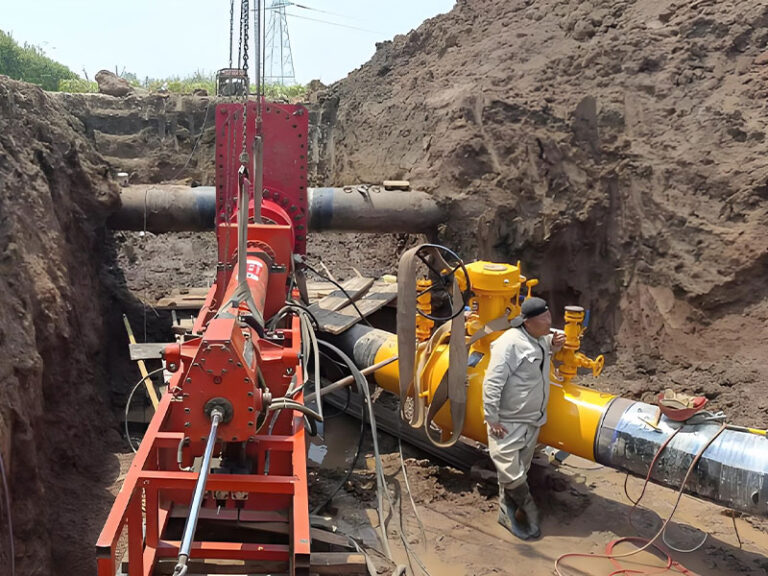 Red hot tapping equipment connected to in-service natural gas pipeline (with yellow fittings) in excavation pit, for live pipeline connection project