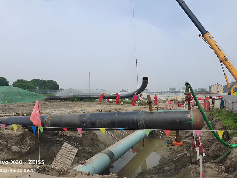 Crane installing pipeline bend during crude oil pipeline relocation construction for integrity maintenance