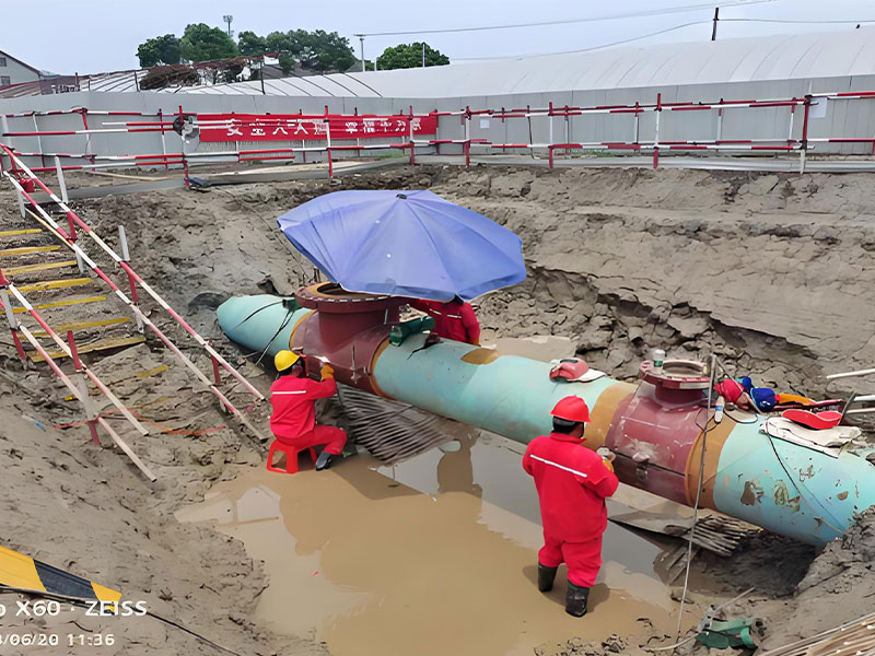 Workers operating on pipeline tee joint during crude oil pipeline hot tapping and plugging services