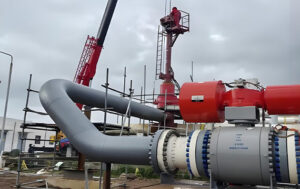 Pipeline (with elbow) connected to hot tapping equipment, with scaffolding and crane ready for under pressure drilling in EPC project
