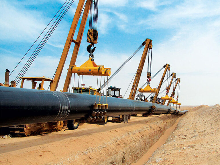 A construction crew using sideboom tractors to lift a 12-inch natural gas pipeline into a desert trench, featuring cost estimation labels for steel, labor, and total price per milefoot.