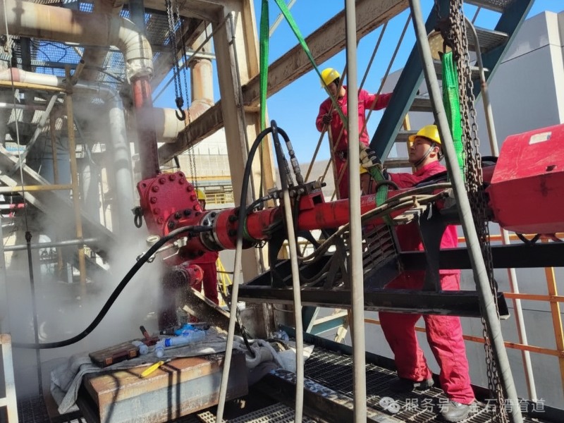 Un equipo de técnicos industriales profesionales con equipo de seguridad rojo y cascos amarillos realizando un procedimiento de roscado en caliente en una tubería roja presurizada en un emplazamiento industrial.