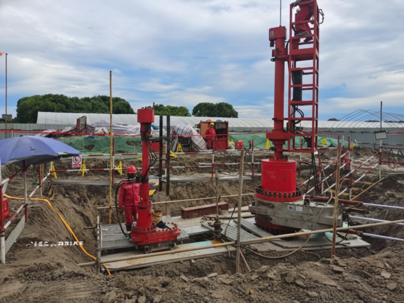 Professional construction crew operating red drilling machinery and trenchless technology equipment for underground pipeline installation at a project site.