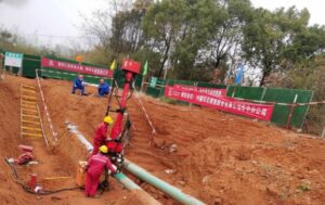 Construction workers operating a red hot tapping machine for DN250 aviation kerosene pipeline plugging and relocation in a trench.