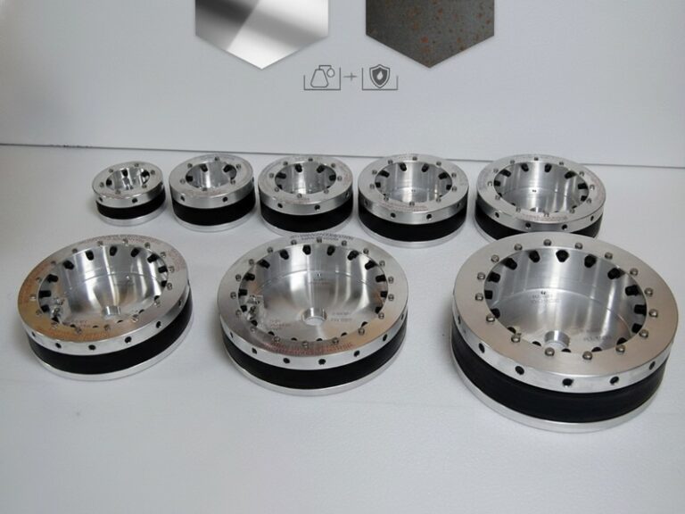 Коллекция промышленных модульных уплотнений для труб различных размеров, с серебристыми металлическими внешними кольцами с болтами и толстыми черными резиновыми прокладками для герметичности.