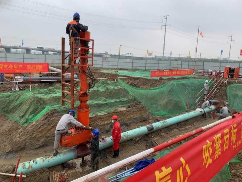 Construction workers operating a large orange hot tapping machine on an oil pipeline during the Anhe and Anbo product oil pipeline diversion project in Shucheng.