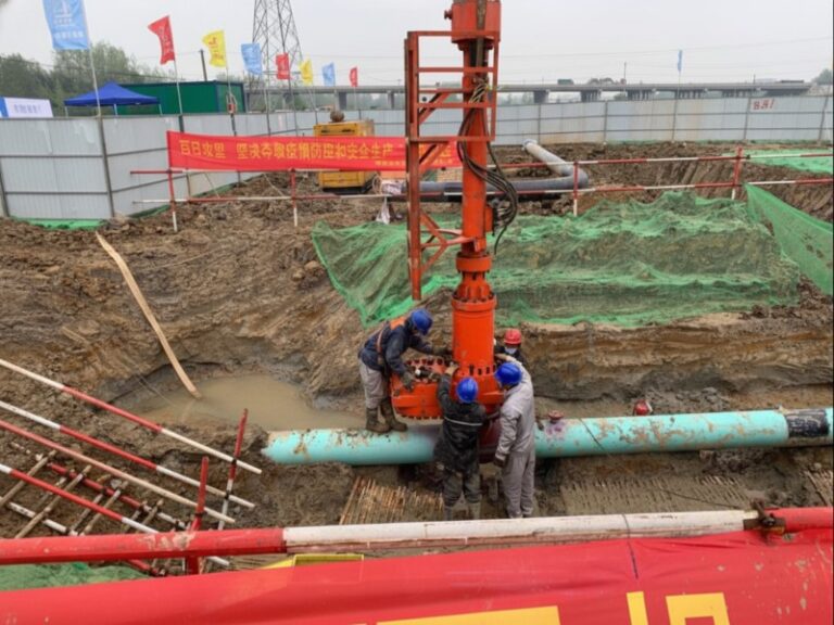 Construction workers operating pipeline plugging machinery on a light blue pipe for the Anhe and Anhao refined oil pipeline relocation project in Shucheng, Anhui.