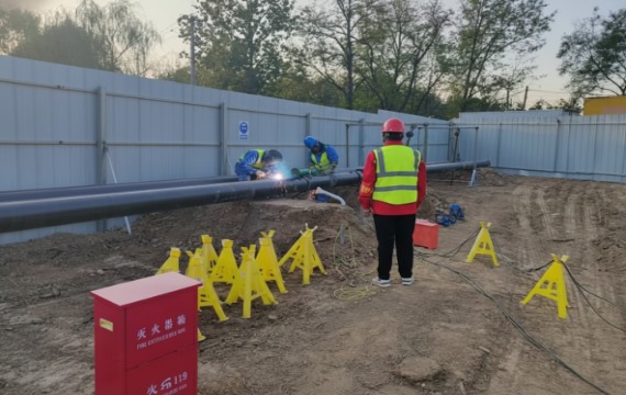 Construction workers wearing safety helmets and high-visibility vests perform welding on the Sinopec and China Aviation Fuel pipelines during the Wenchao Jianhe relocation project.