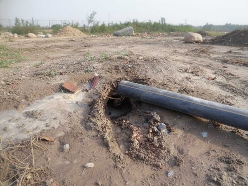 A black pipe being installed using the pipe jacking method at a muddy outdoor construction site for trenchless utility work