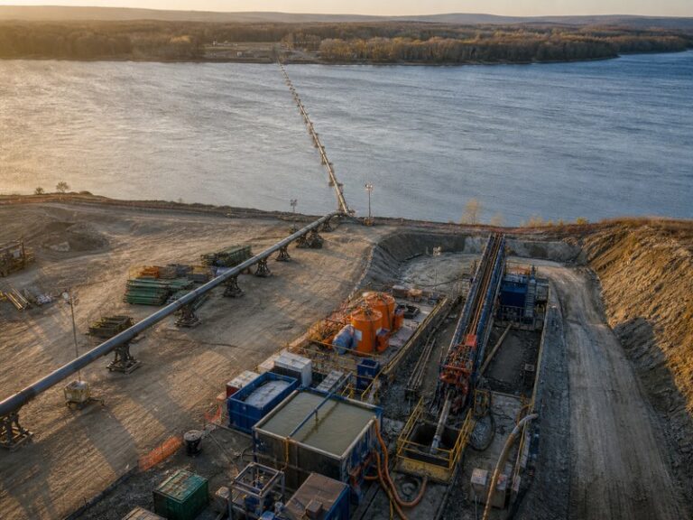 Aerial view of a record-scale HDD river crossing with a long steel pipe string feeding toward the river