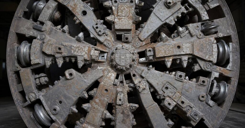 Mixed ground cutterhead on a microtunnel boring machine with carbide-tipped chisel teeth, scrapers and disc cutters mounted together on the faceplate