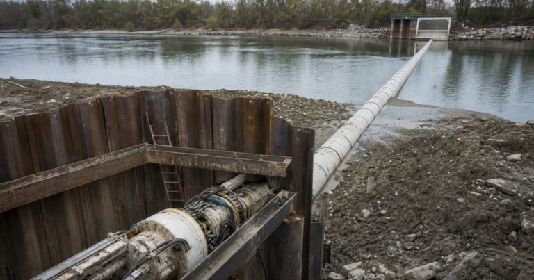Microtunneling machine launching from a riverbank shaft to install a water transmission main toward an intake structure