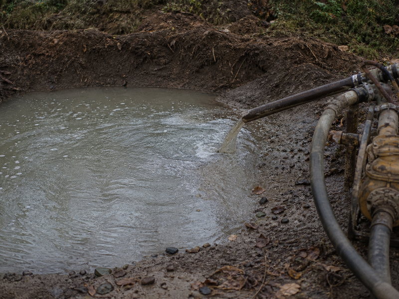 Drilling fluid returning from an HDD borehole carrying a reduced cuttings load, indicating a cuttings bed forming at a low point