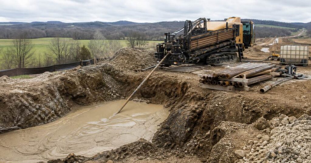 HDD drilling rig operating over a pipeline crossing with drilling fluid return at the entry pit